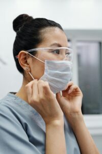 tcae female healthcare worker putting on a protective mask indoors, emphasizing health and safety.